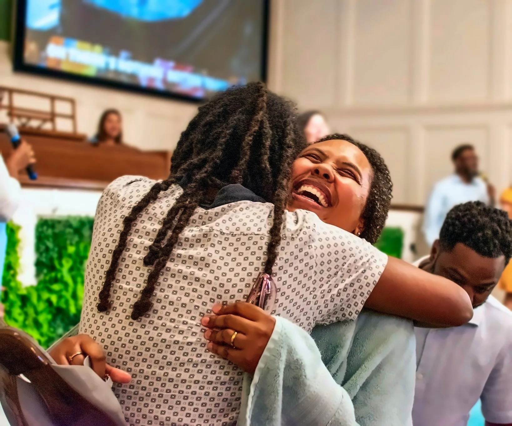 Two women sharing a joyful hug in the sanctuary
