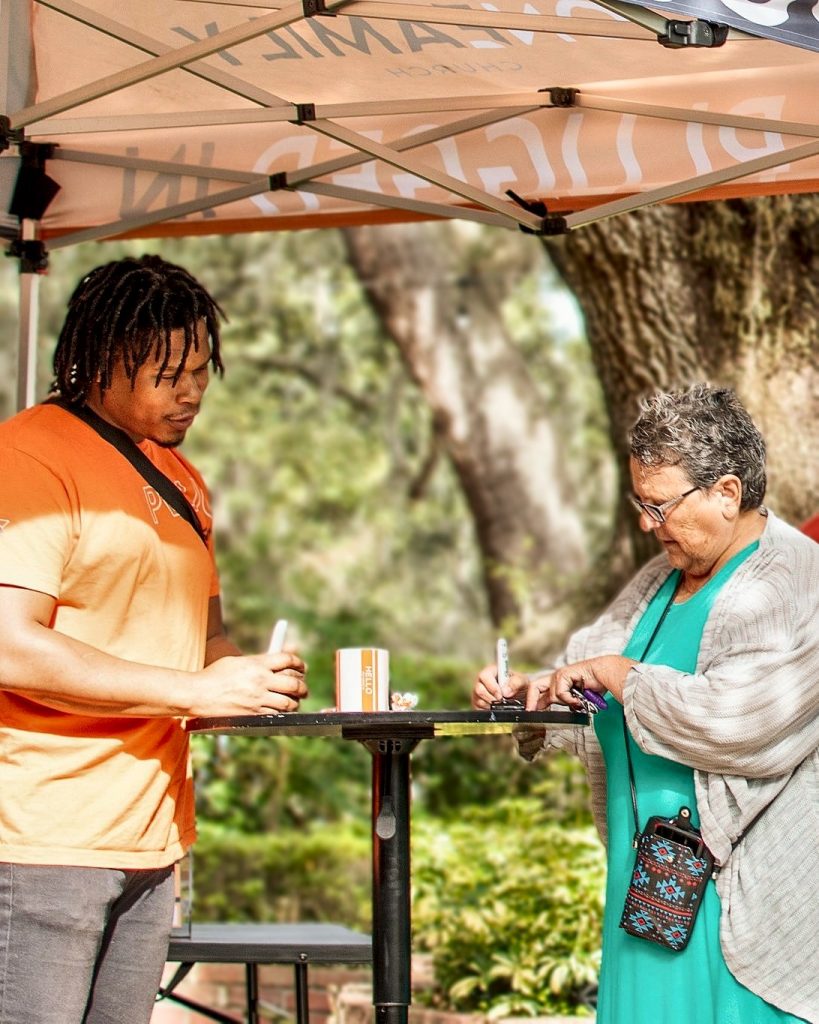 A volunteer at the welcome tent greeting a guest before the Sunday service
